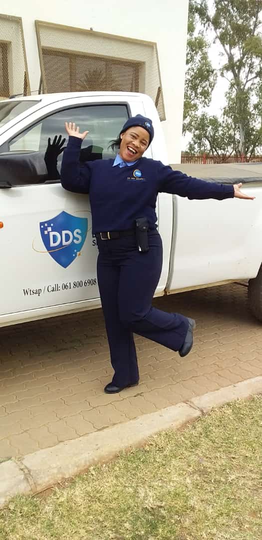 Security officer posing joyfully next to DDS branded vehicle