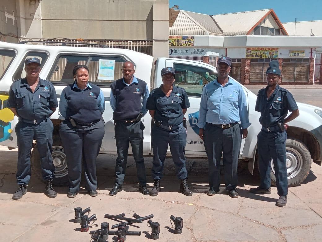 Security officers lined up with equipment by patrol vehicle